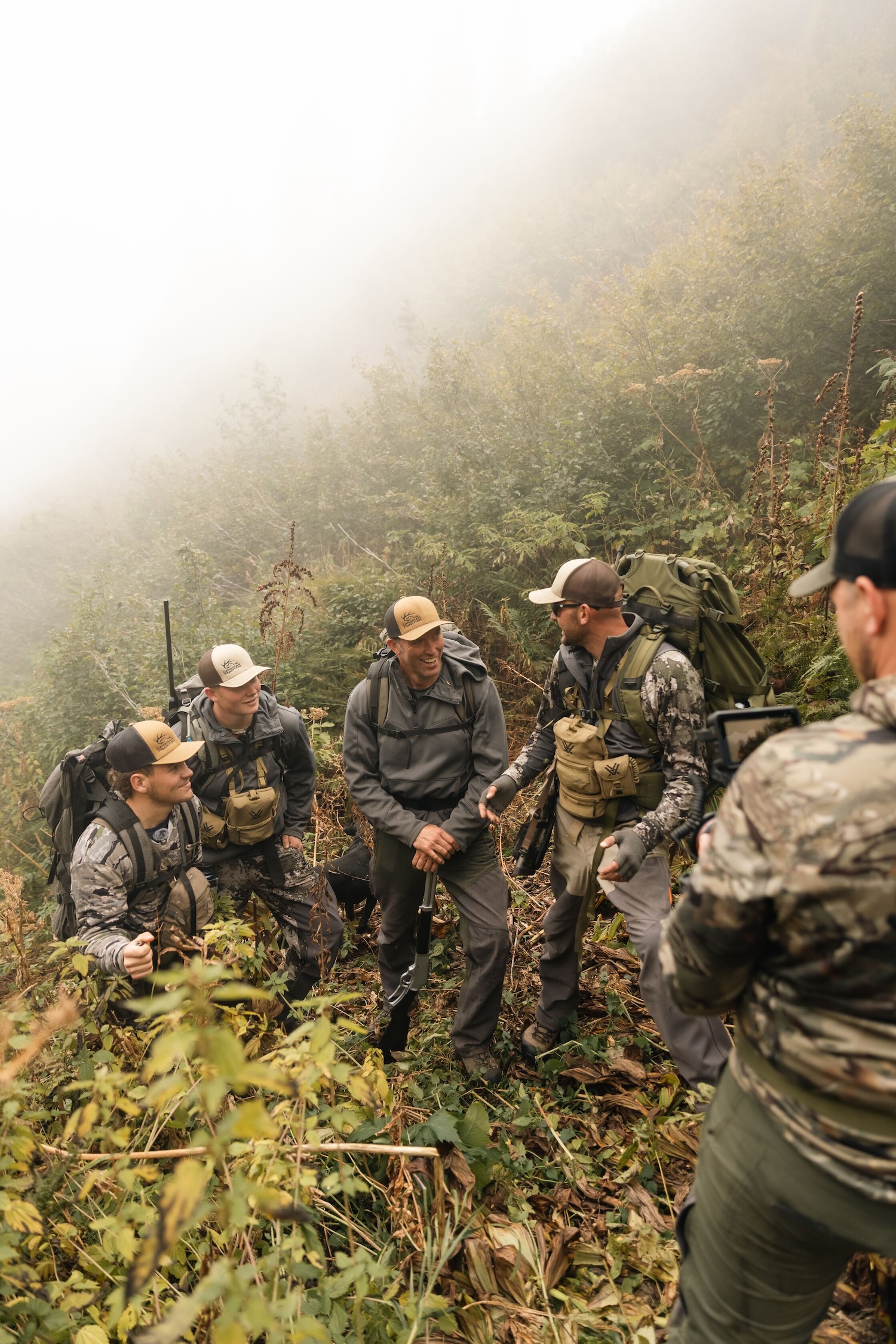 Several hunters with gear on a hill. 