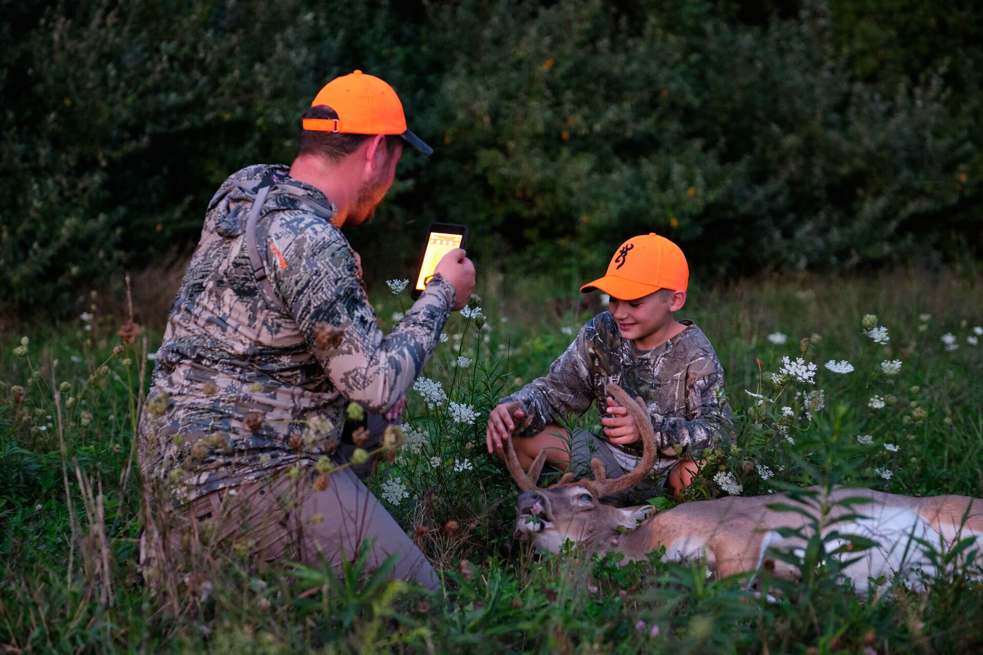 Man takes photo of boy with deer after hunt. 