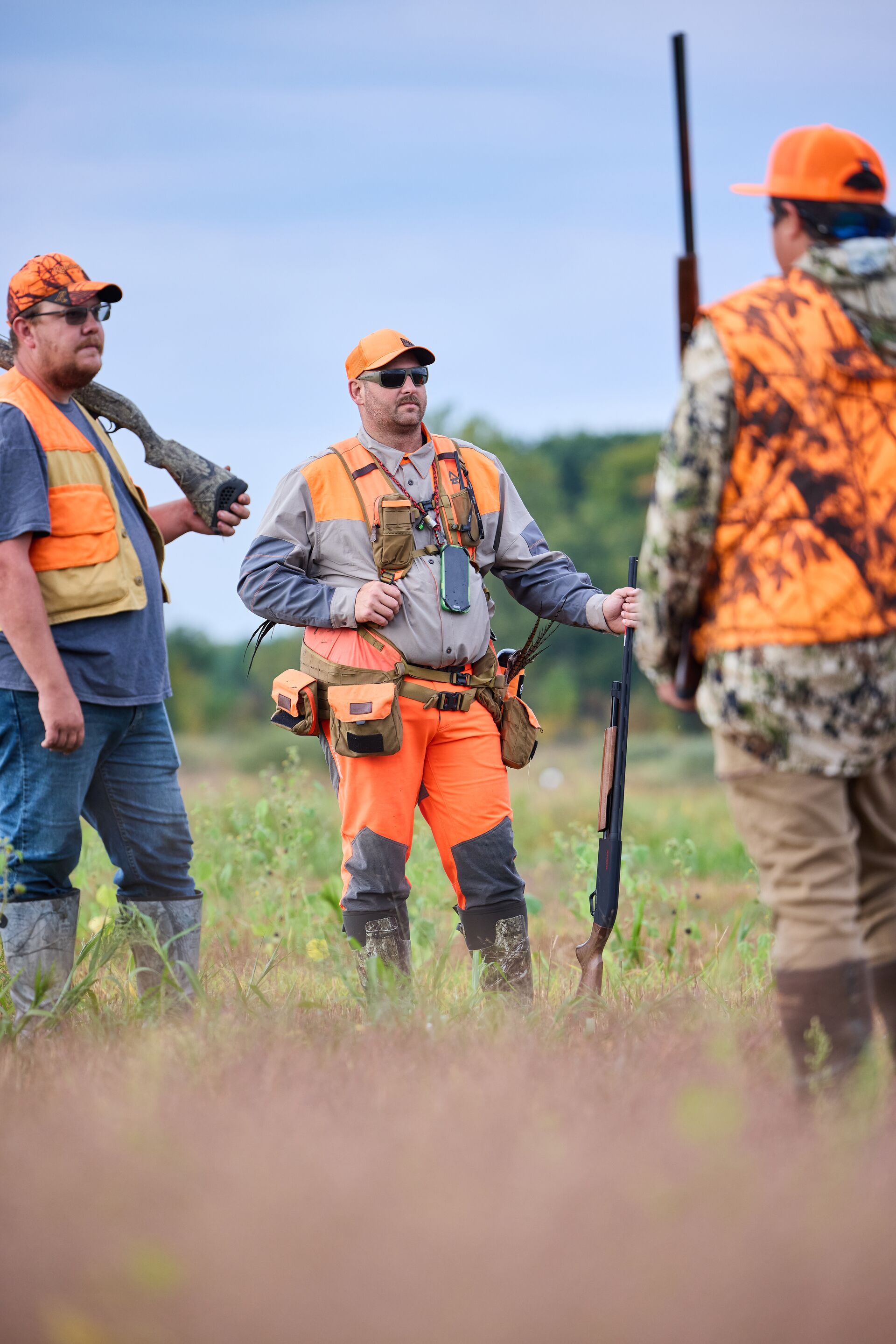 Three hunters in blaze orange in a field before a hunt. 