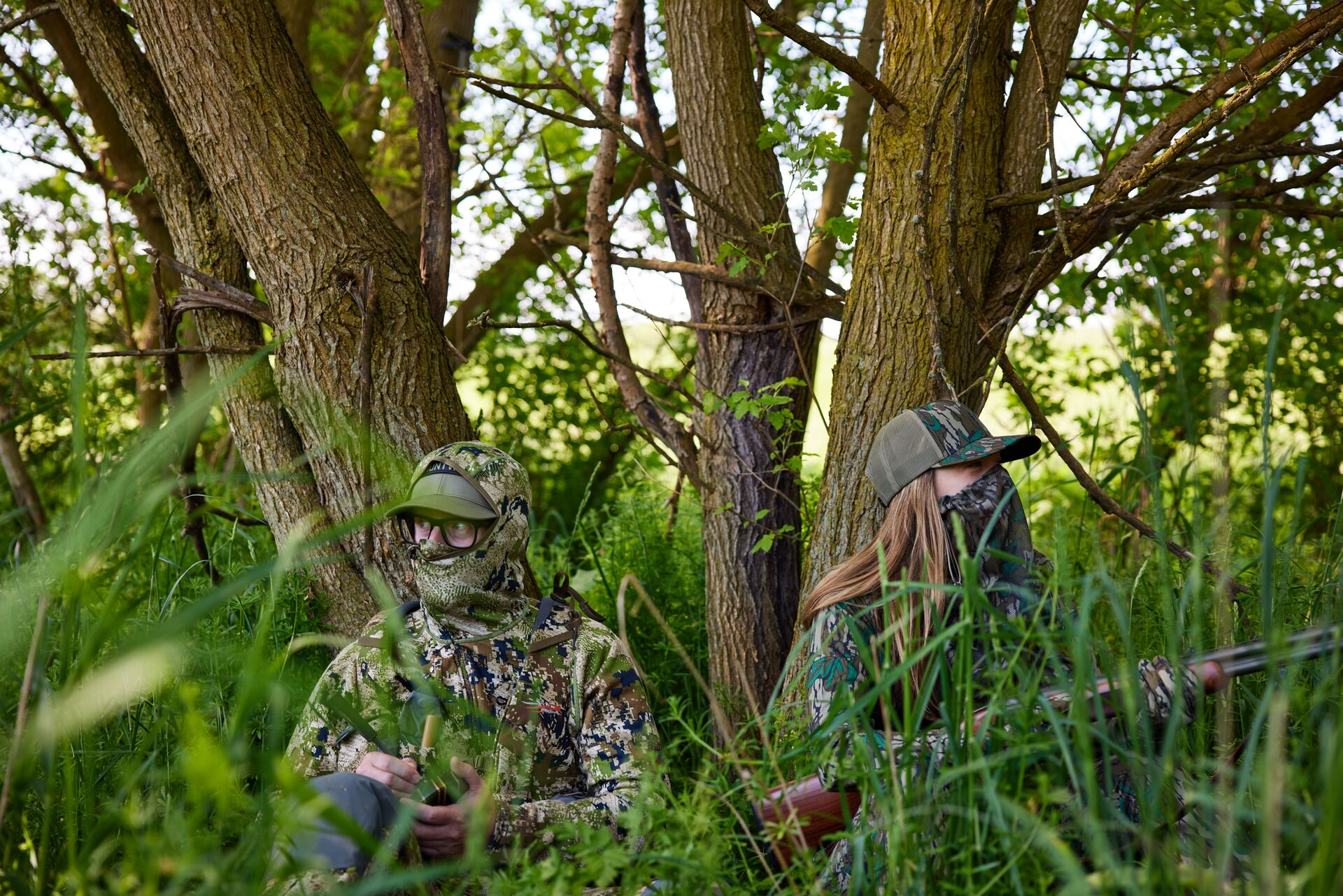 Two hunters concealed in tall grass for hunt, get a Michigan apprentice hunting license concept. 