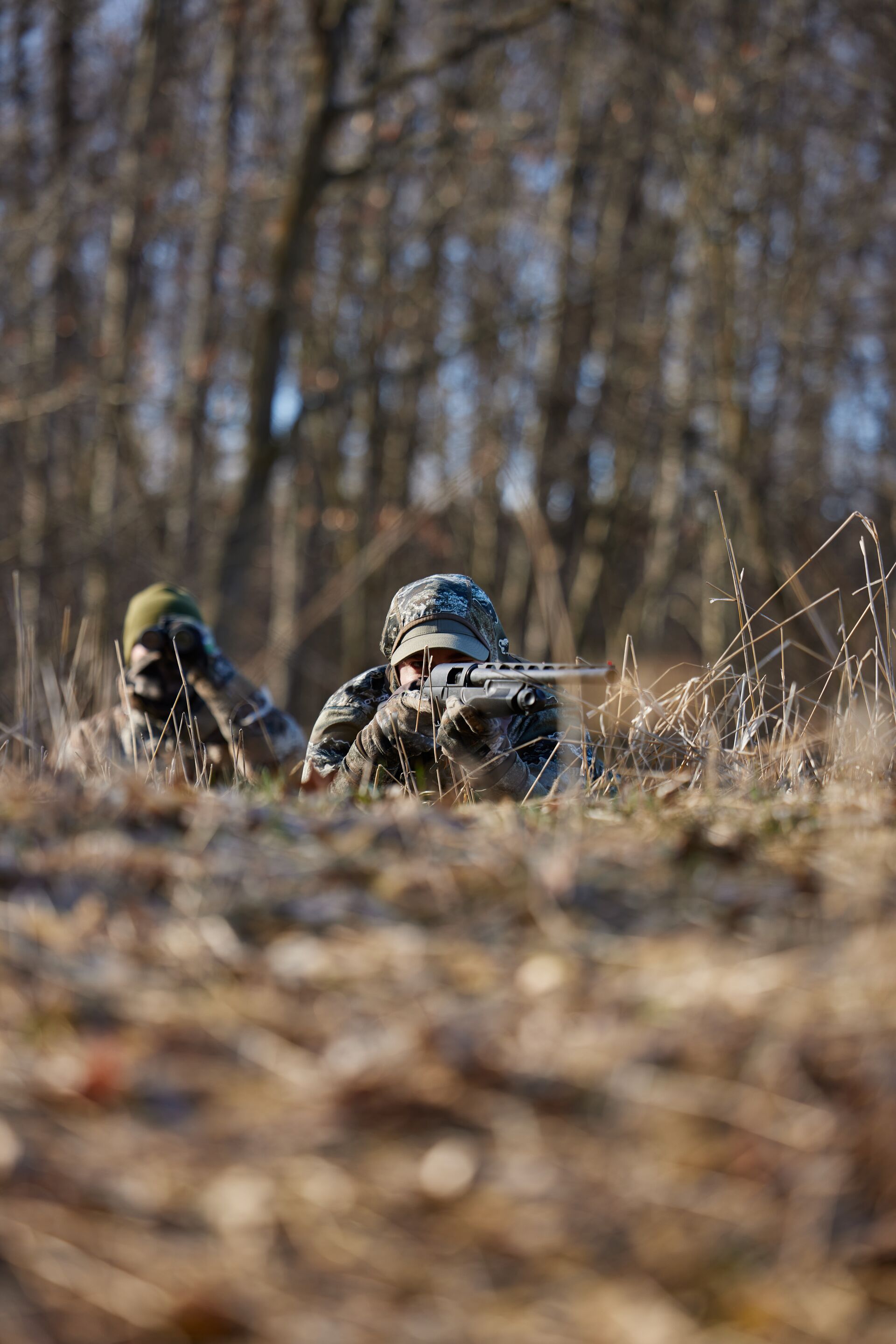 Hunter aims shotgun with another hunter nearby, Indiana apprentice hunting license concept. 