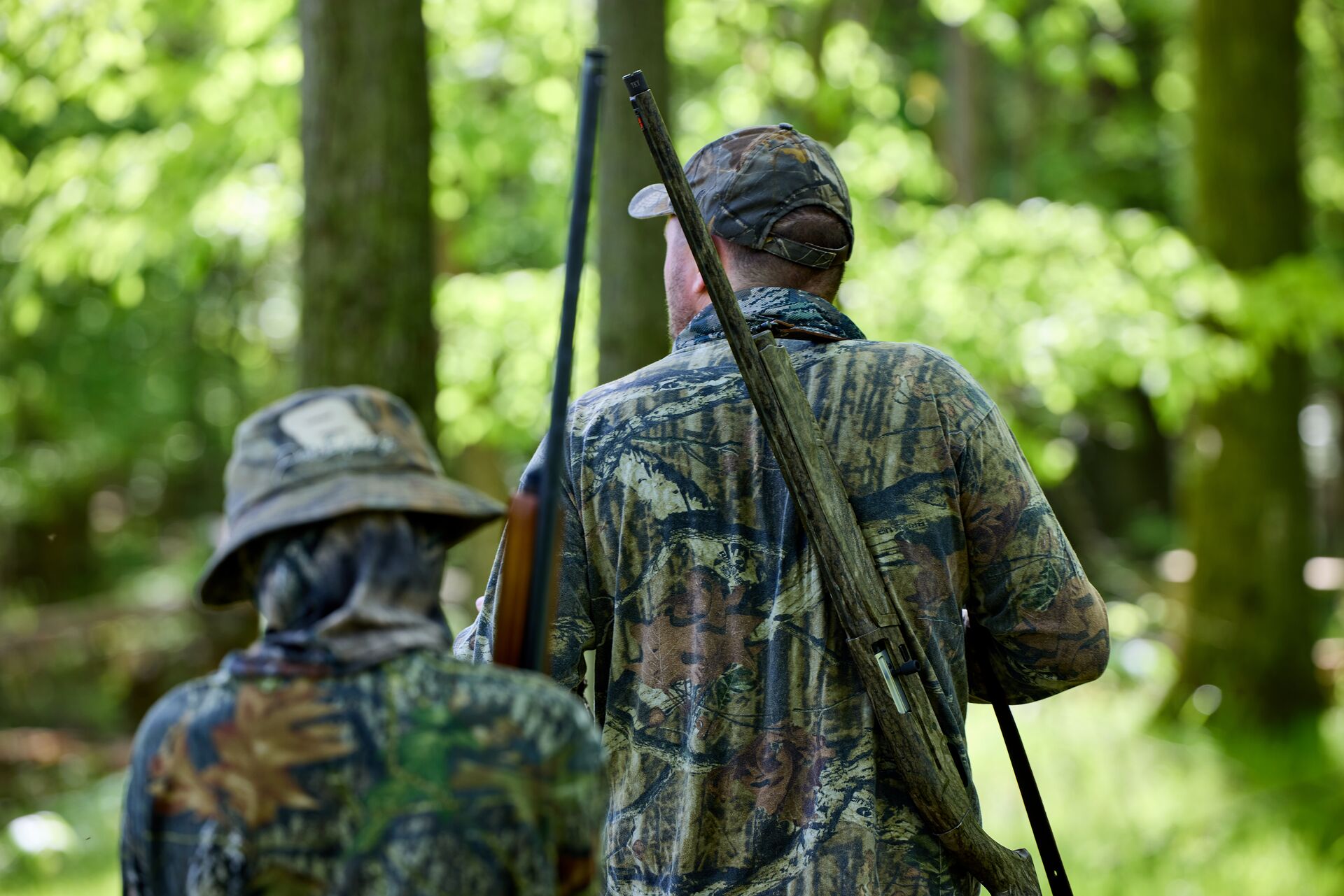 Adult and boy in camo hunt in the woods. 