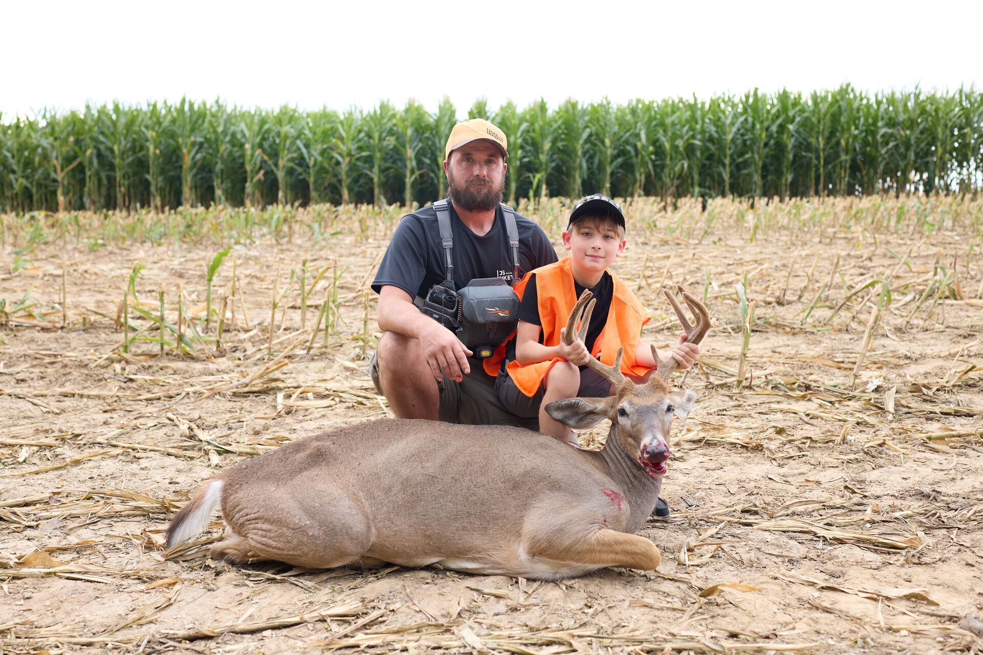 Man and boy on the ground with a buck deer after hunt, Indiana youth hunting license concept. 