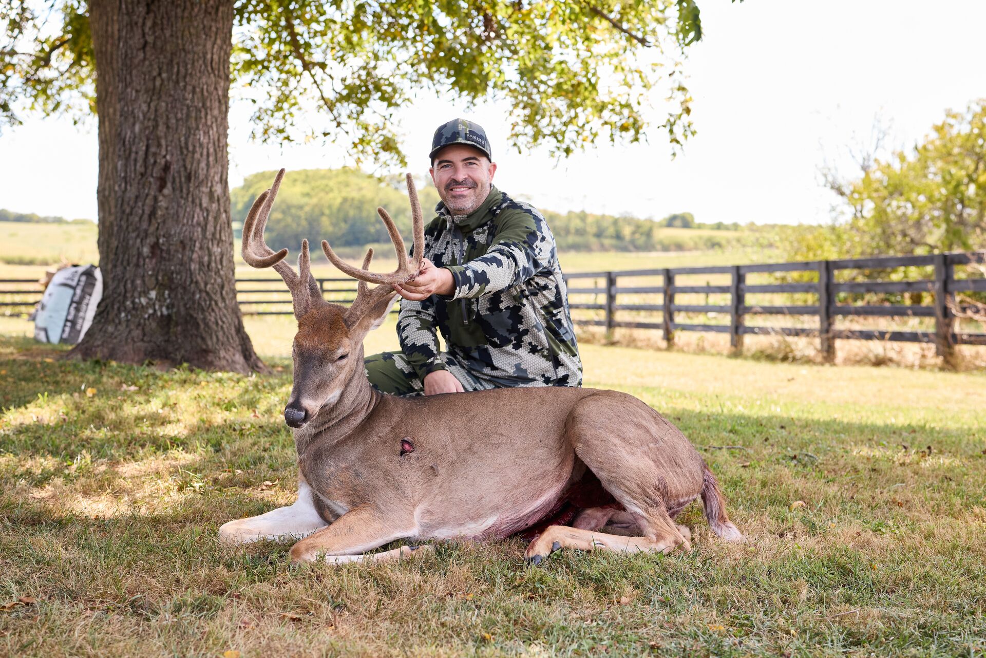 Hunter smiles with buck deer after hunt, get a Arkansas hunting license concept. 
