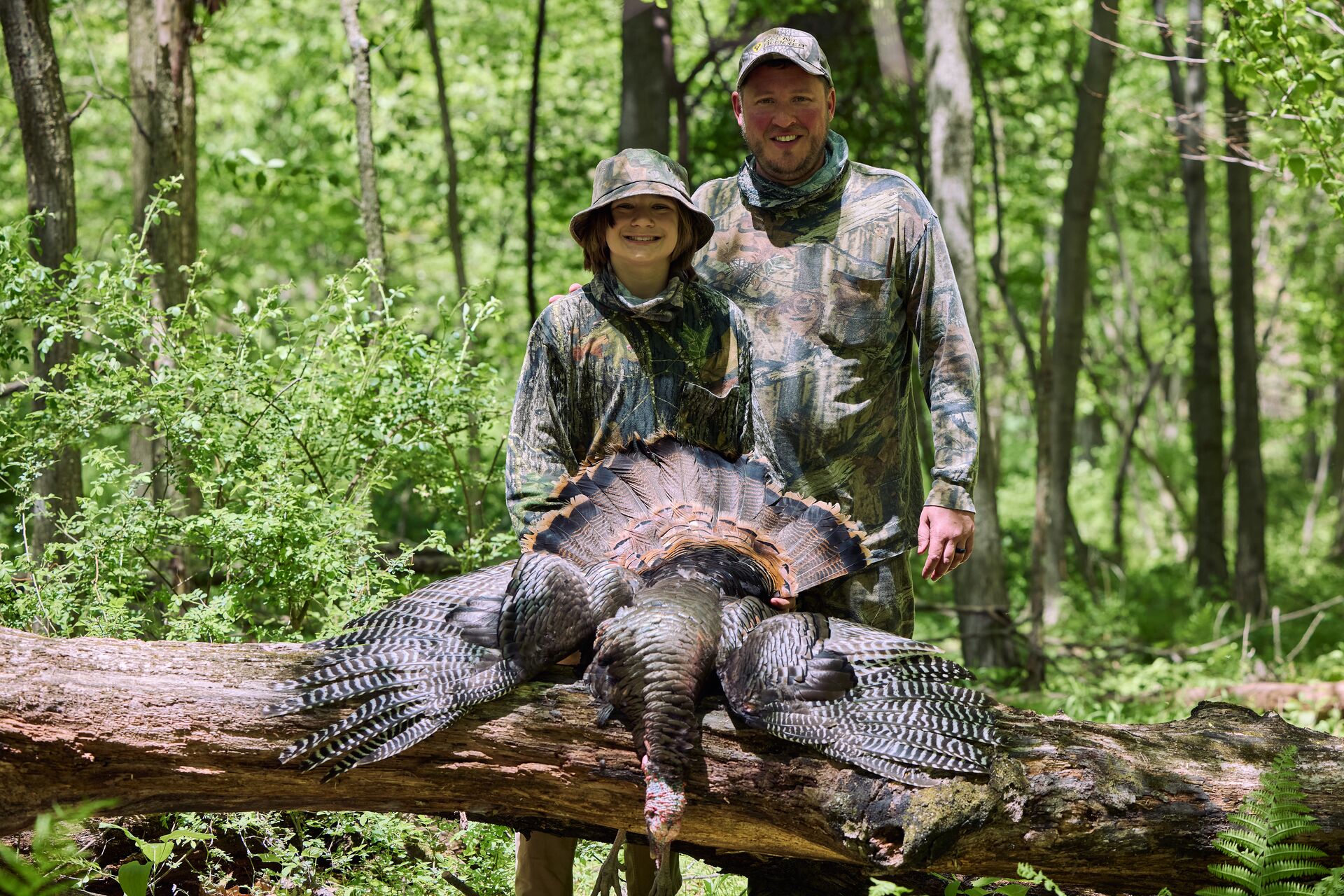 Adult and boy with turkey on log after hunt, Oklahoma youth hunting license concept.