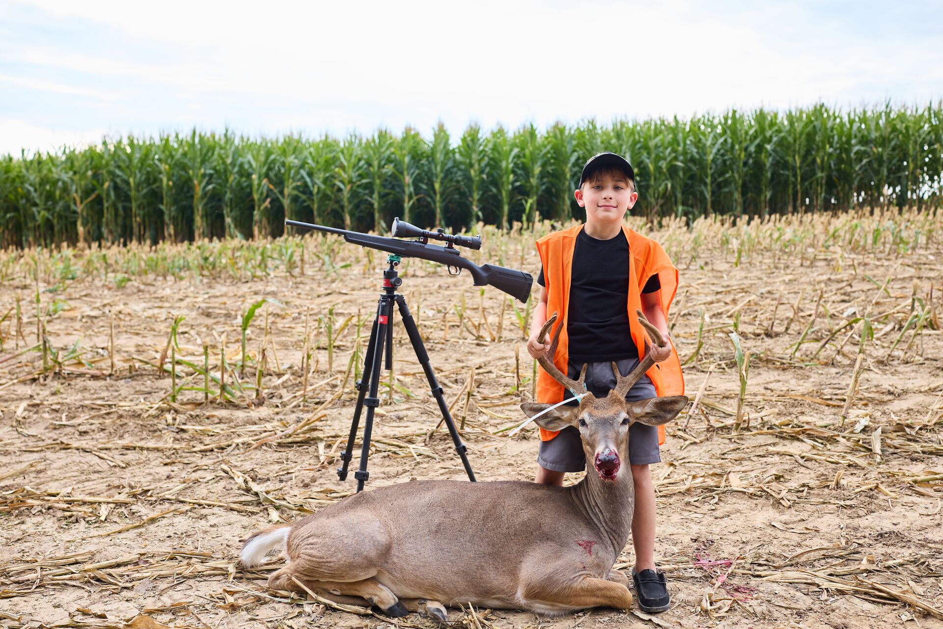 Boy poses with buck deer and rifle after hunt, Georgia youth hunting license concept. 