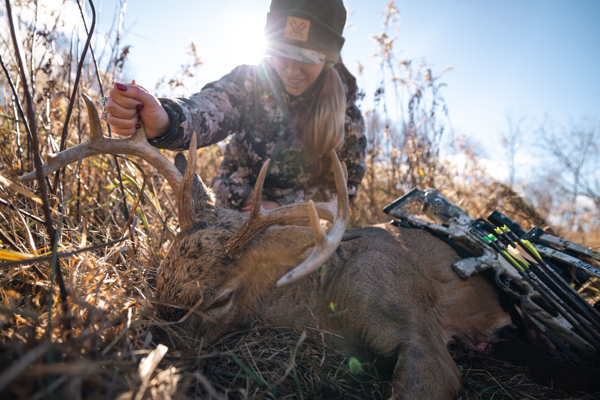 Female hunter sits with buck deer and bow after hunt, first time hunter checklist concept.
