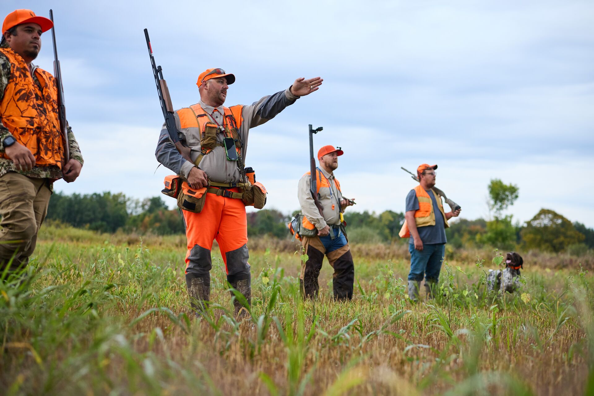 Hunters in blaze orange ready for upland hunt, online vs in-person hunter safety concept. 