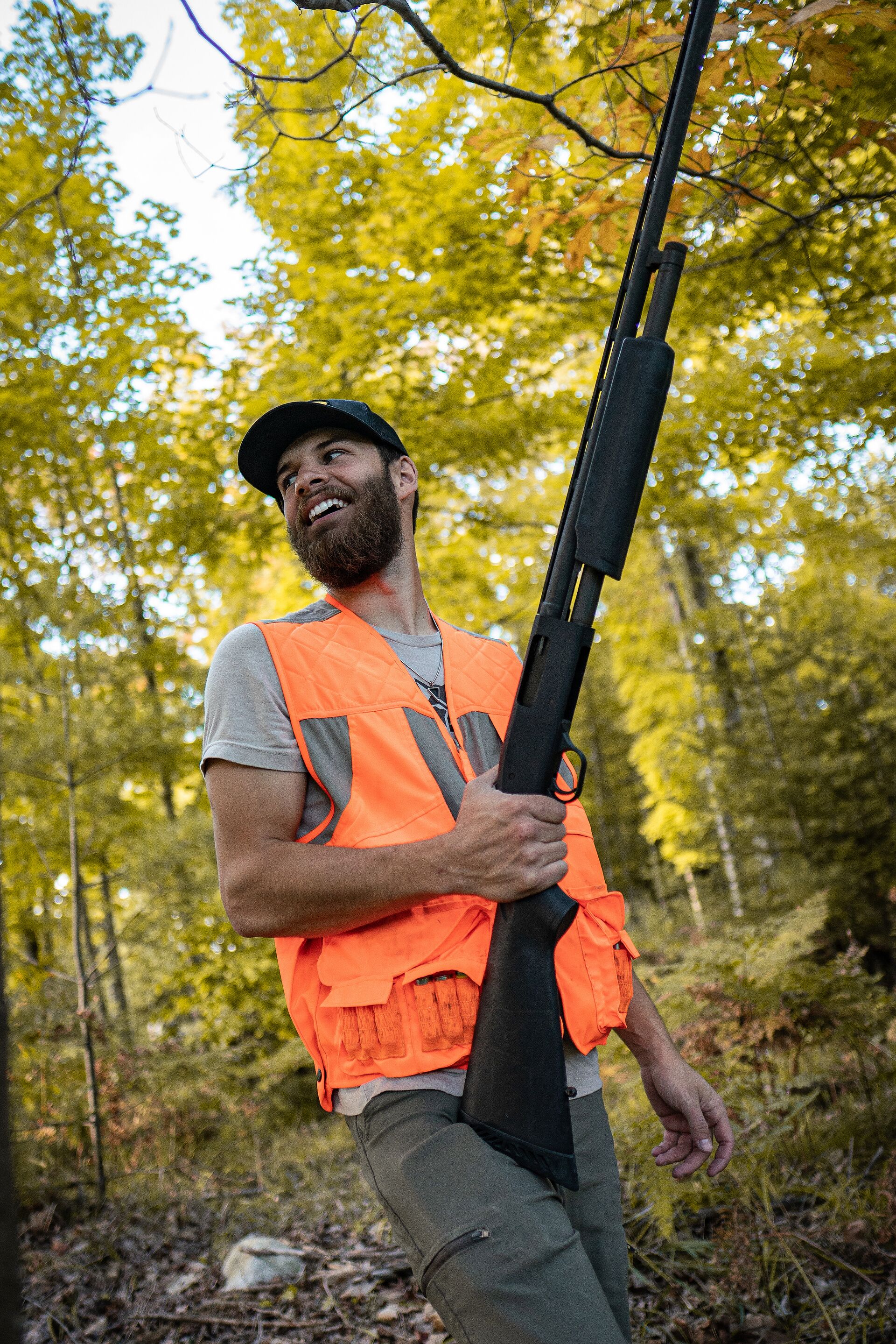 Hunter in blaze orange vest holds firearm, hunter education and firearm safety concept. 