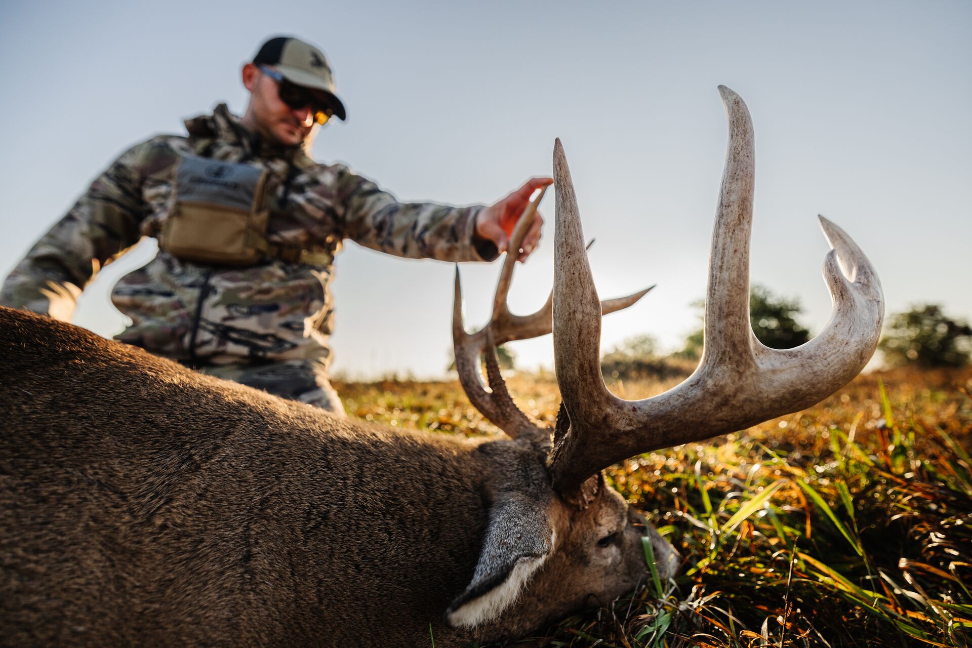 Hunter touching buck deer antlers after hunt.