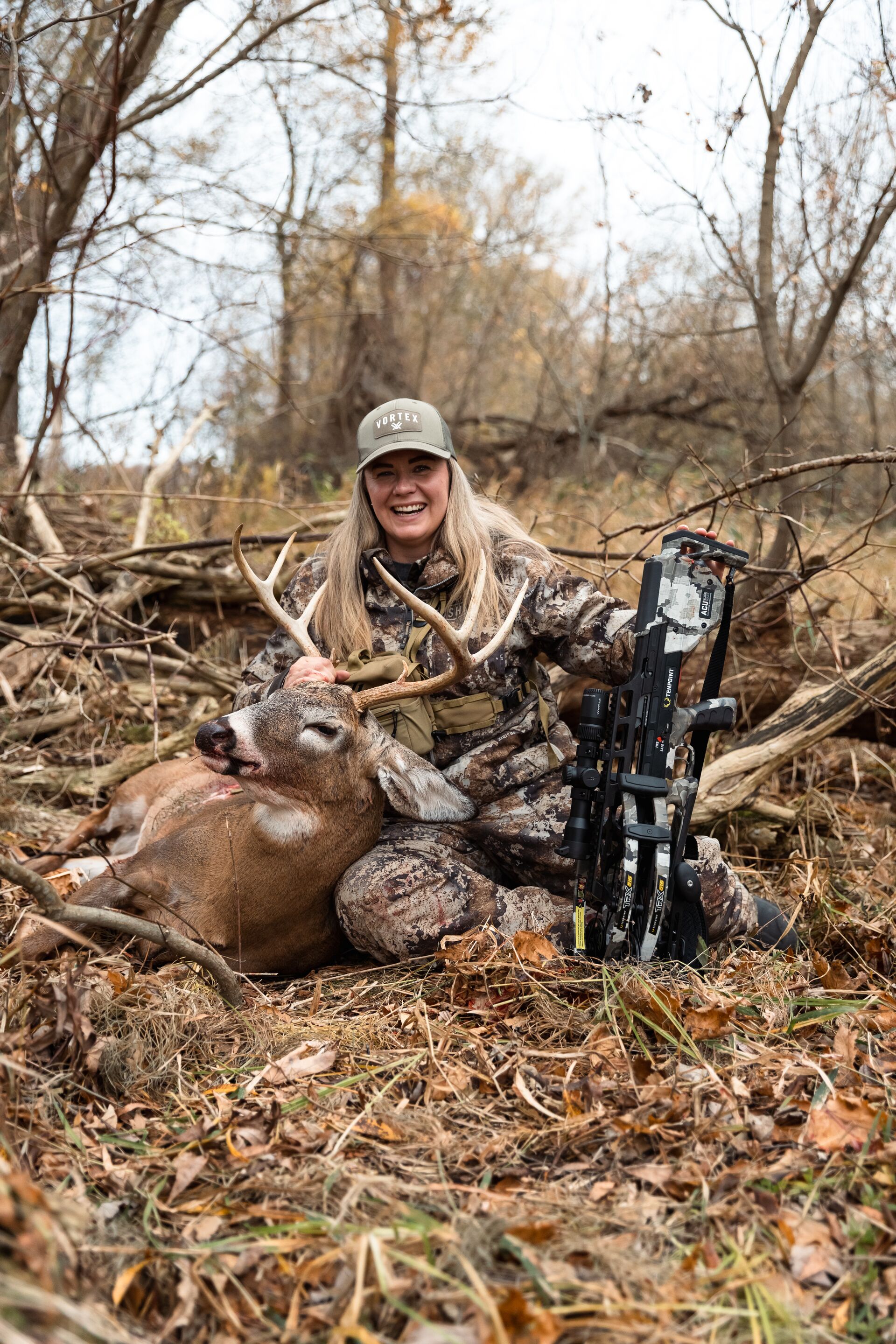 Female hunter with buck deer and bow on the ground after hunt, what is hunter safety concept.