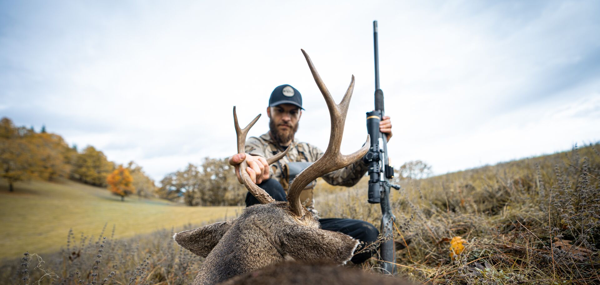 Hunter on the ground looks at buck deer, how to start hunting as an adult concept.