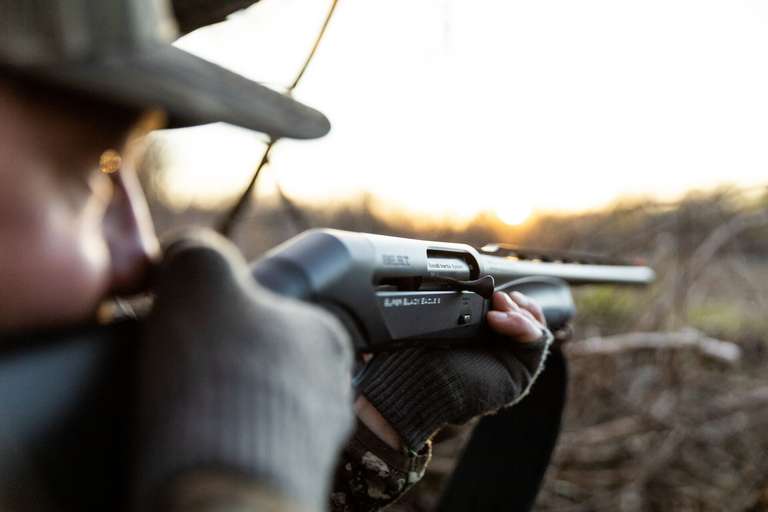 A hunter aims a shotgun, using sights on shotgun firearms concept.