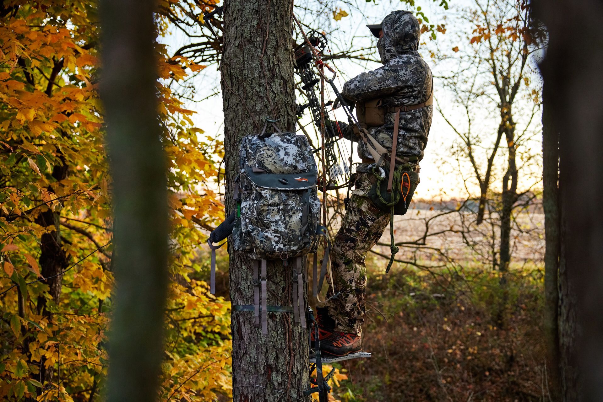 A hunter wearing camo in a tree stand with gear pack, what makes hunting a safe outdoor activity concept.