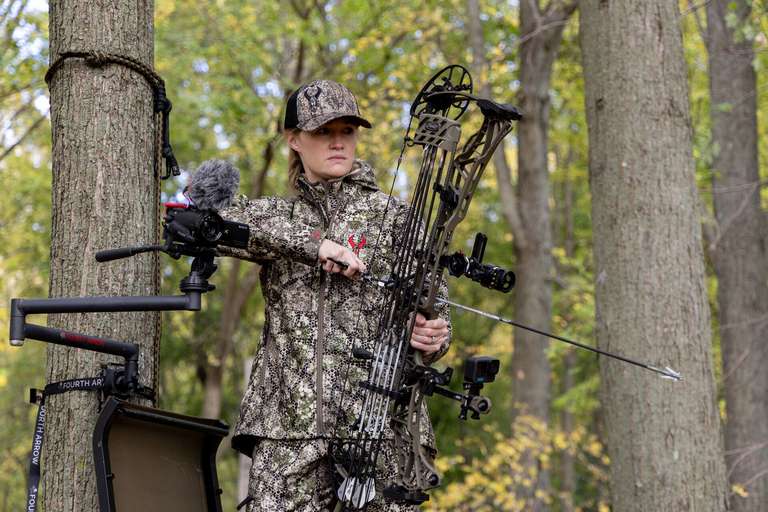 A female hunter with a bow in a tree stand, hunting with a single pin sight concept. 