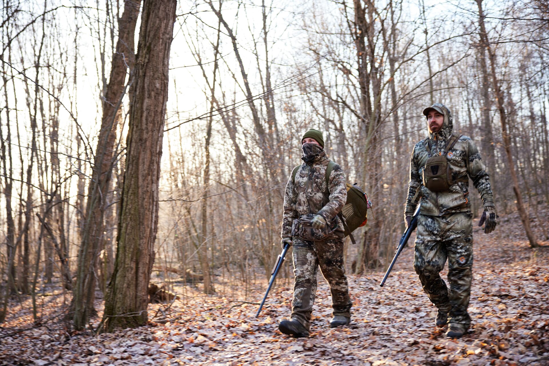 Two hunts walk through woods carrying shotguns, the zone of fire in front of each hunter concept. 