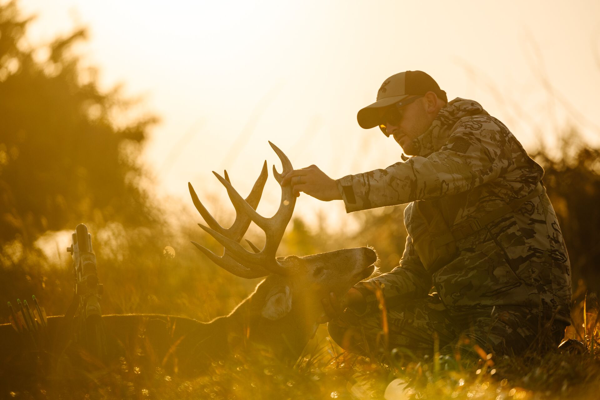 Hunter raises antlers of deer on the ground, broadside shot concept.