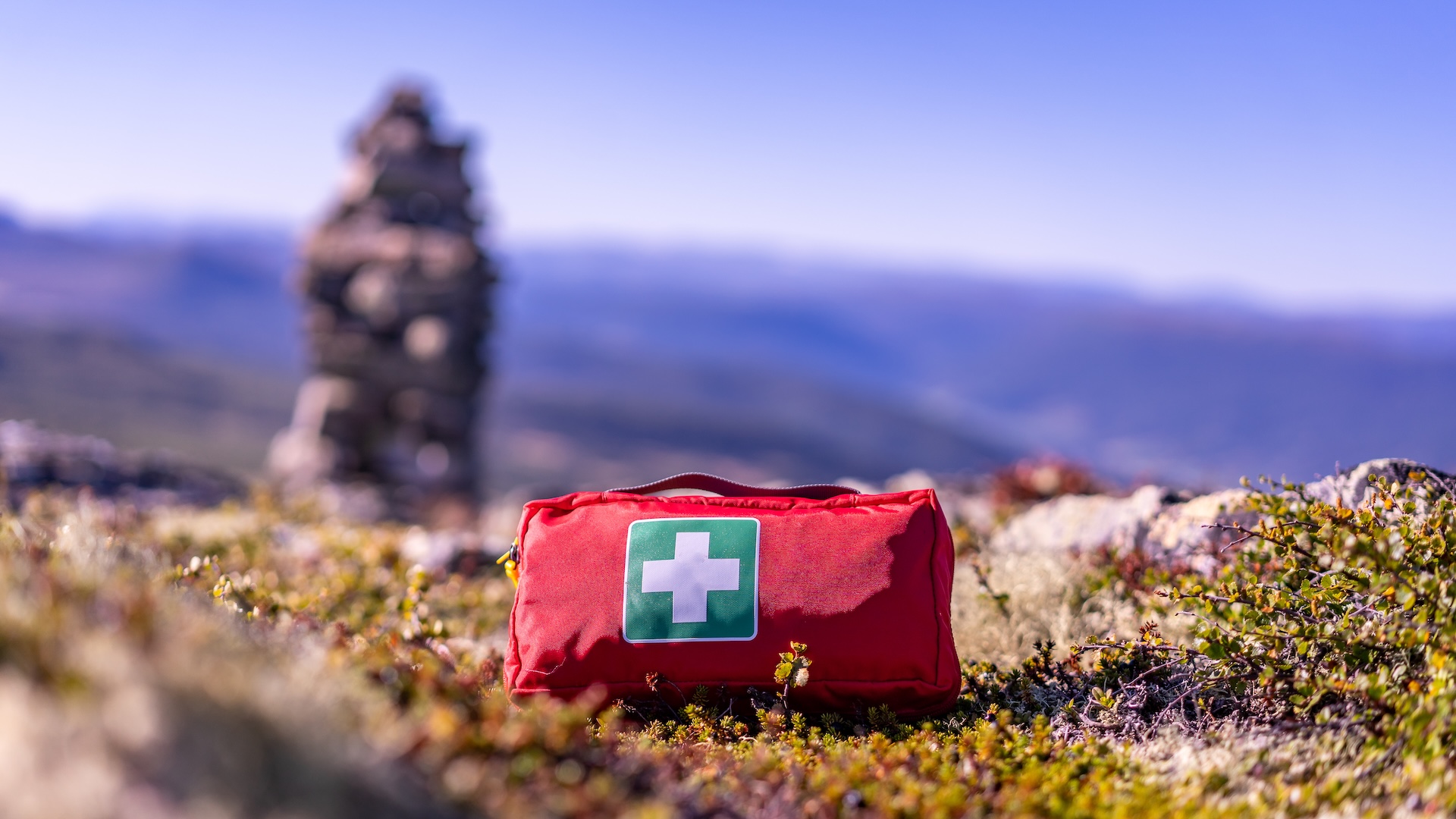 First aid kit sits on the ground with hunter in background.