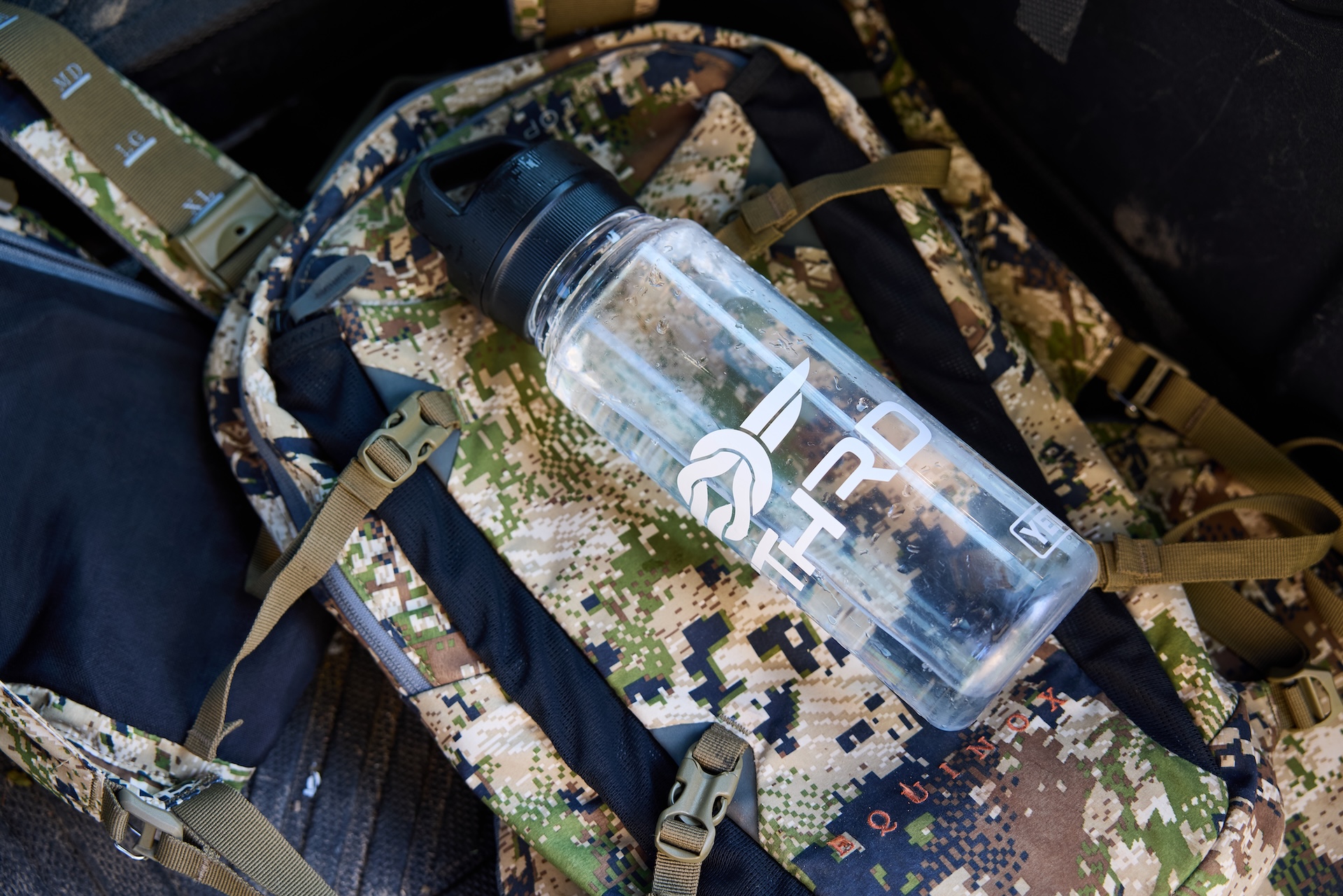 A water bottle lays on a hunting pack, hunting tips for beginners concept. 
