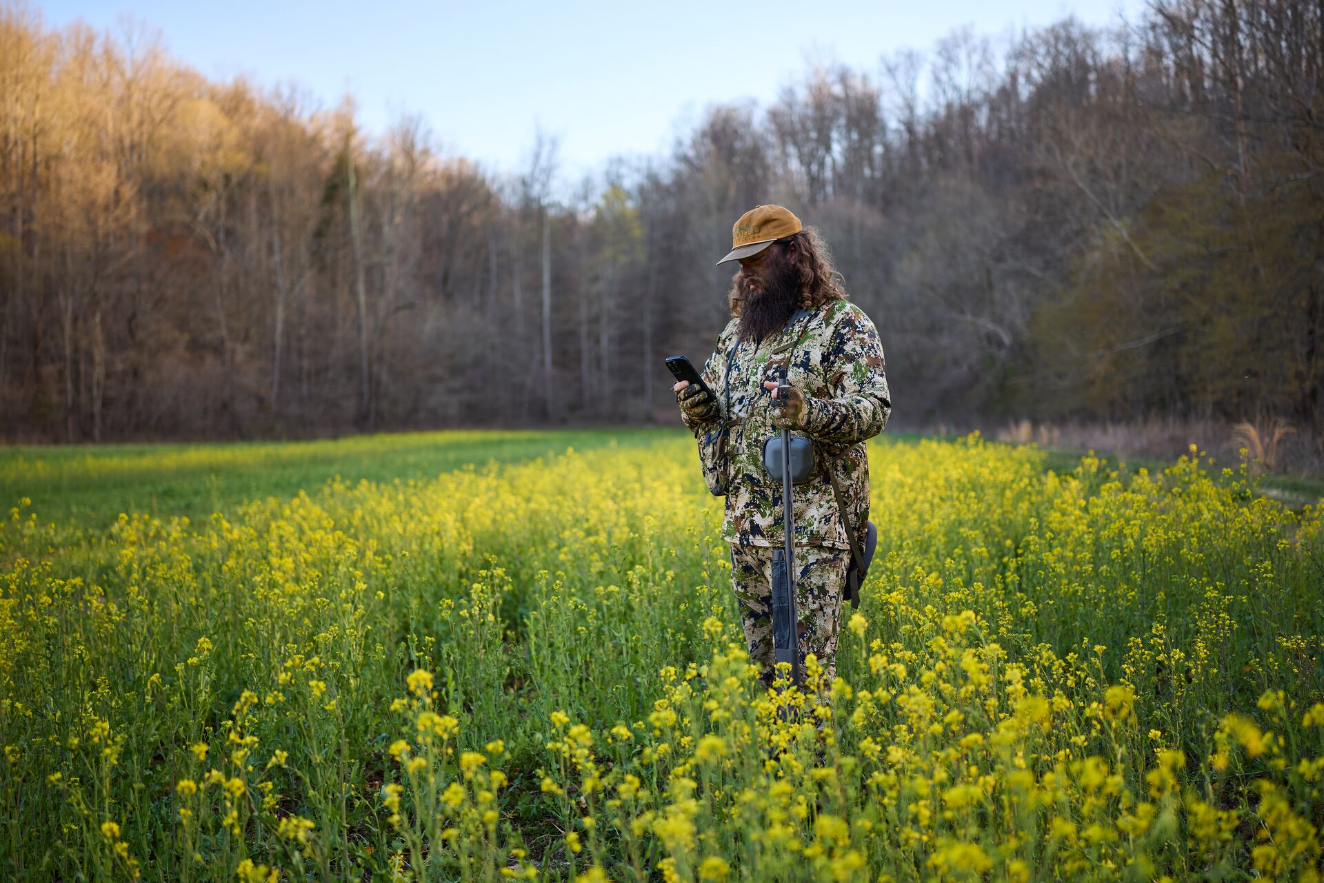 Hunter in a field uses a phone to find where to hunt. 