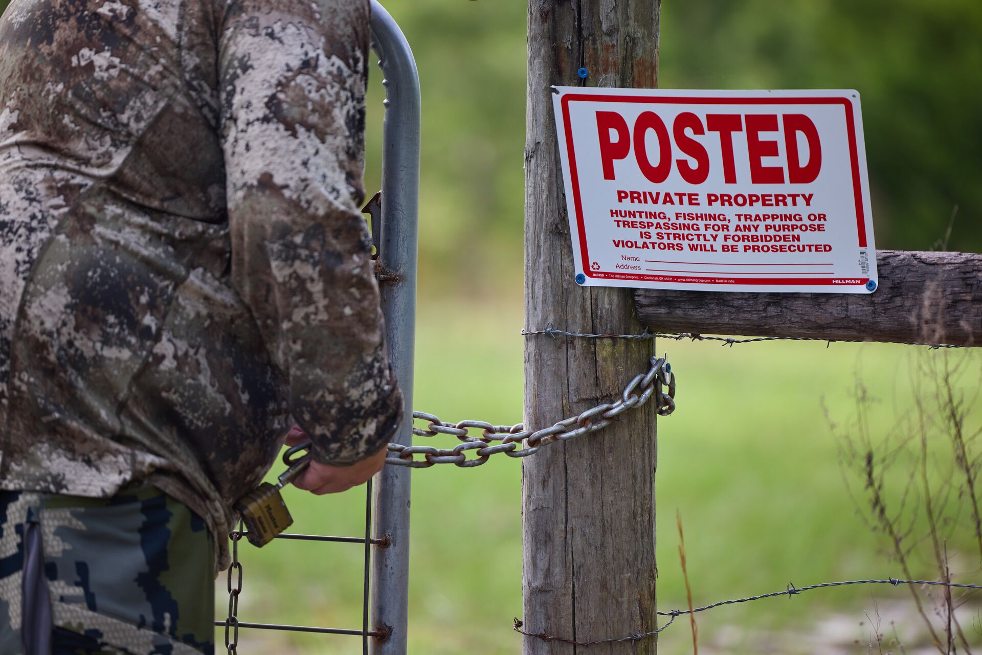 Hunter near a no trespassing sign on a fence.