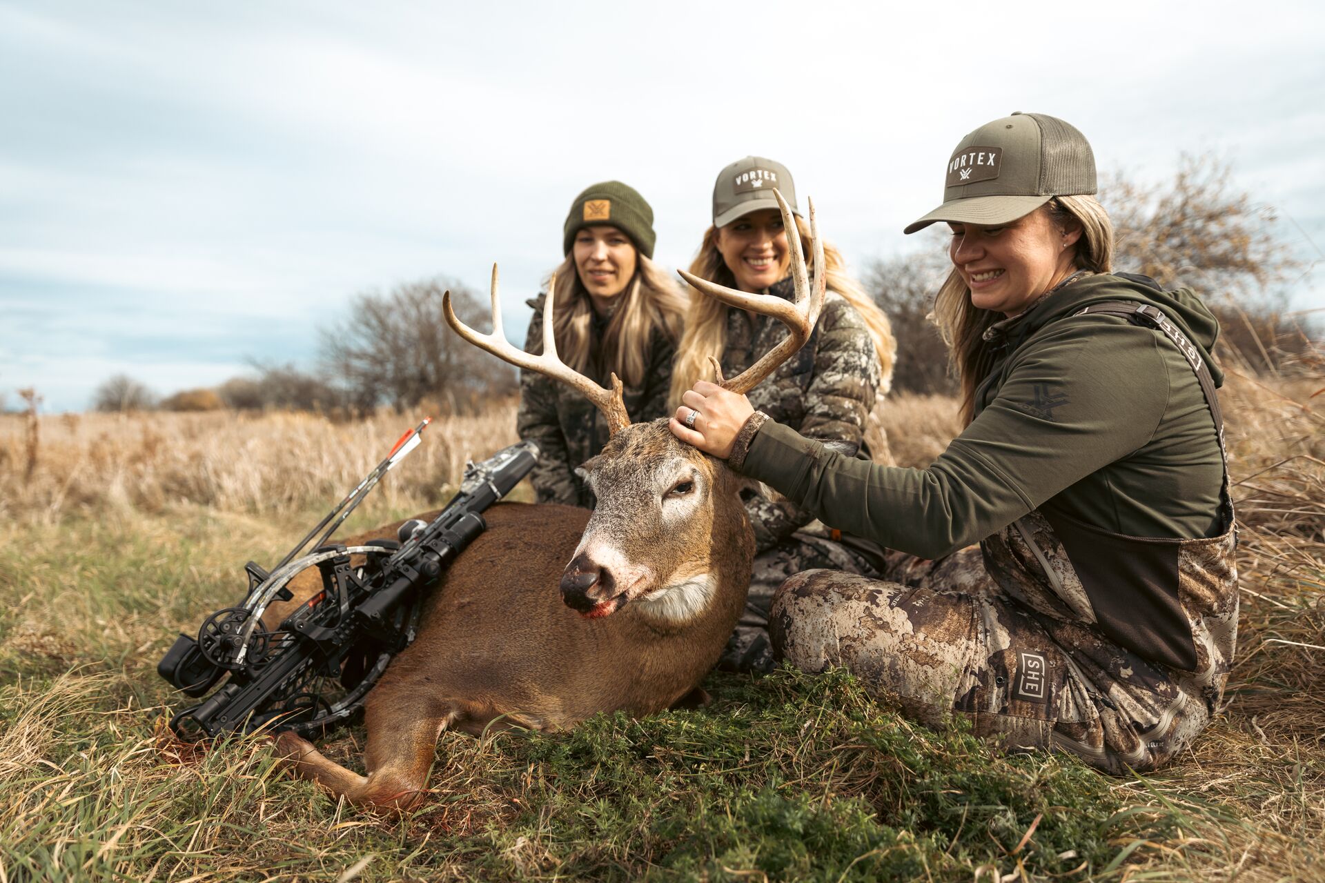 Three female hunters with deer after hunt. 