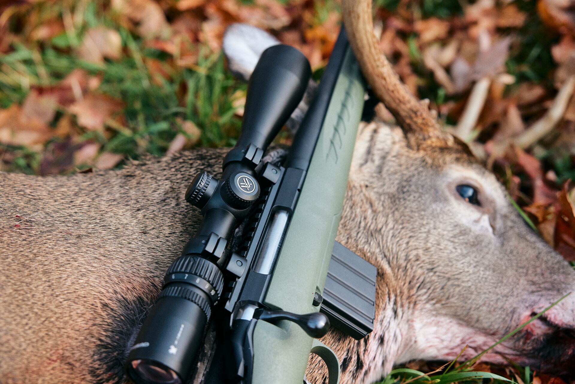 Rifle laying on a deer after a hunt. 