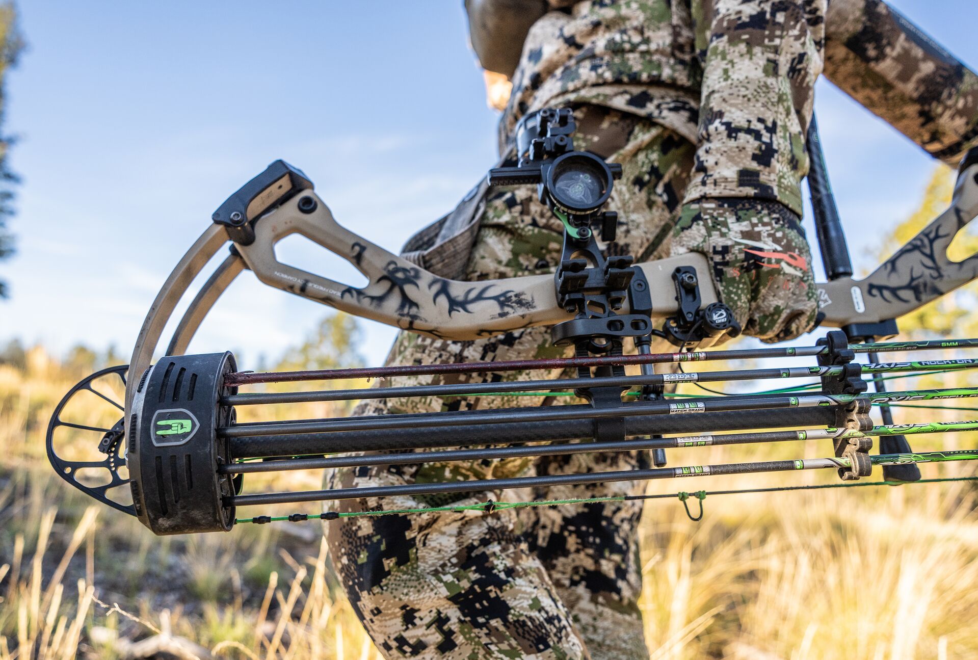 Close up of a bow with arrows at a hunter's side. 