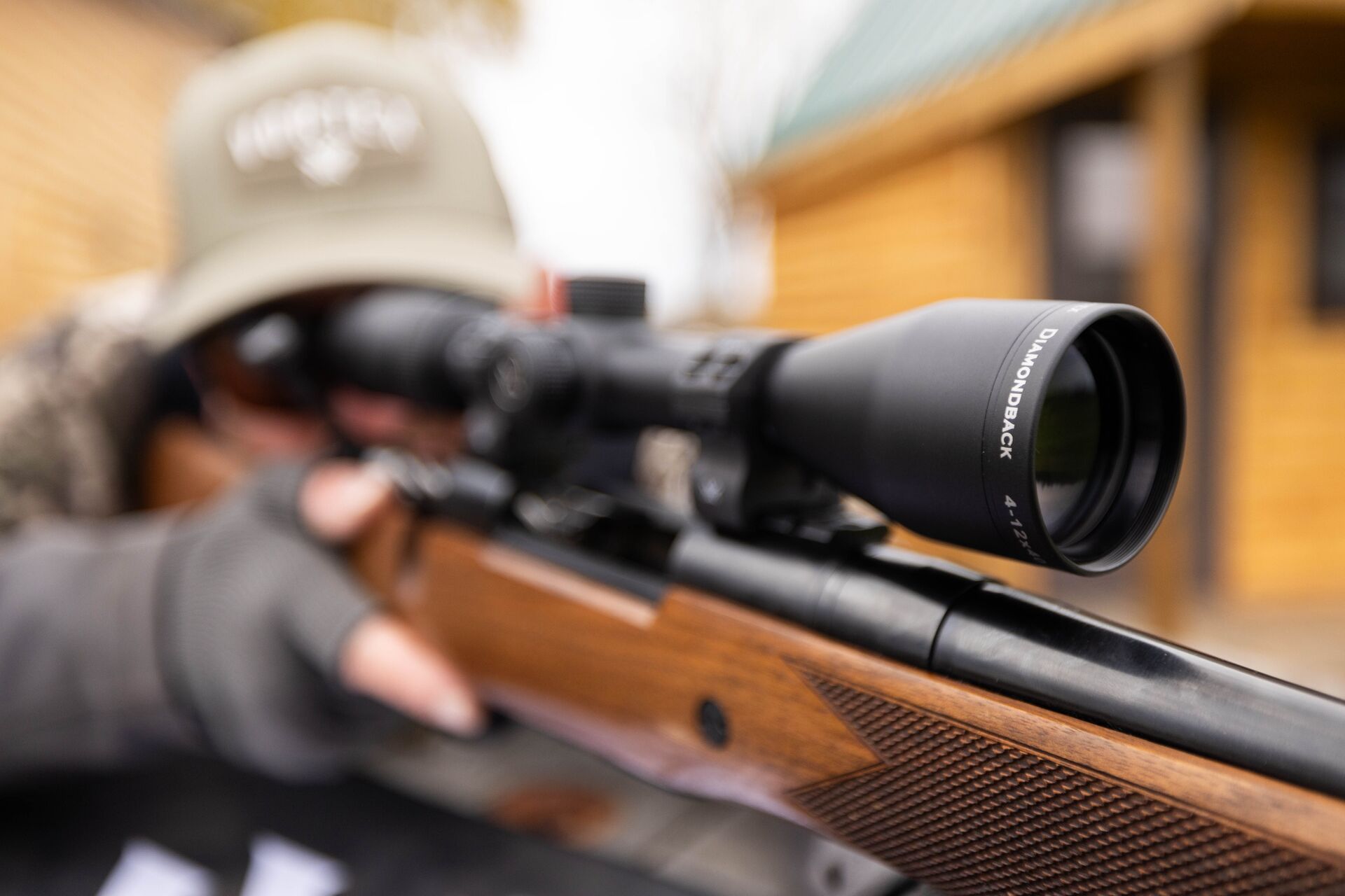 Close-up of a scope on a rifle while a hunter aims it.