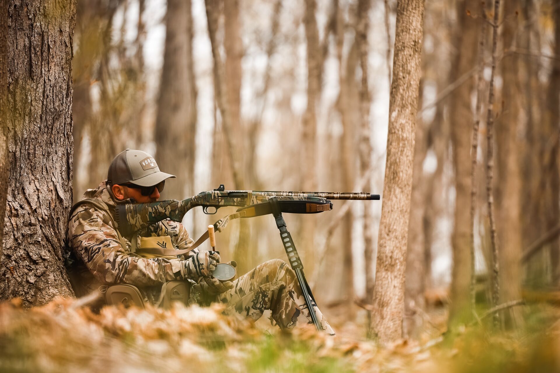 Hunter aims a firearm while in the woods. 