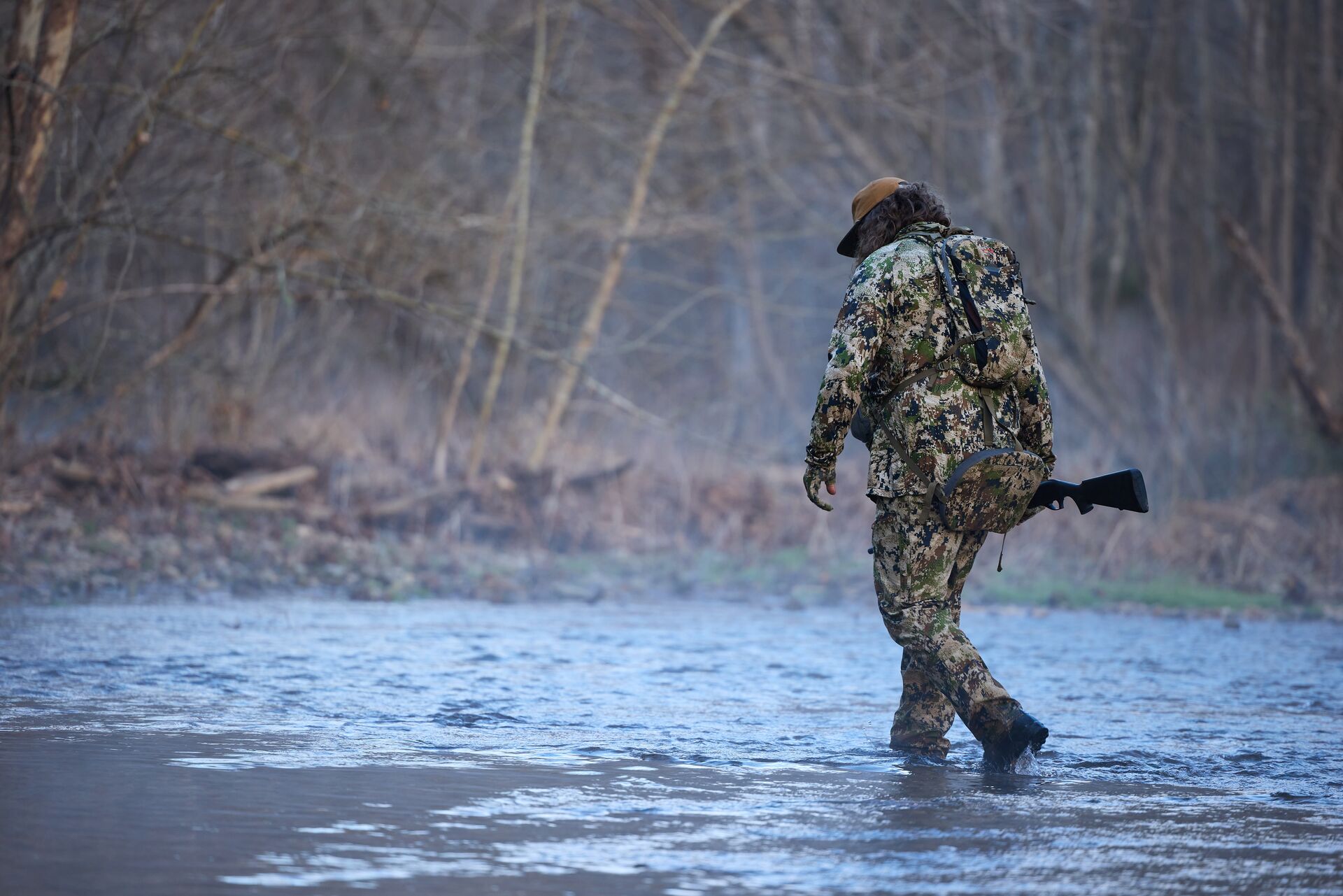 Hunter in camo walking through water, how to start hunting concept. 
