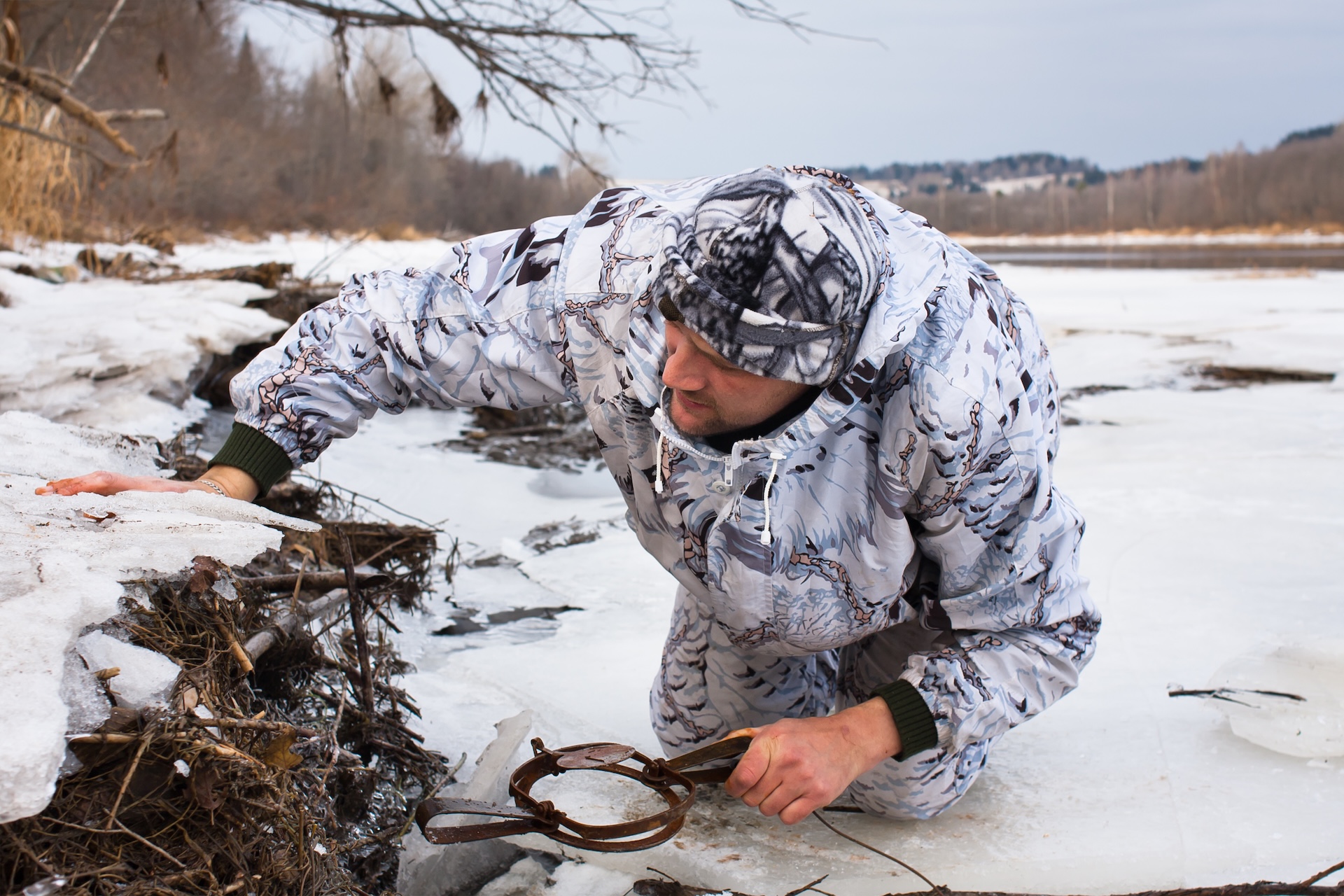 Hunter sets a trap in the snow.