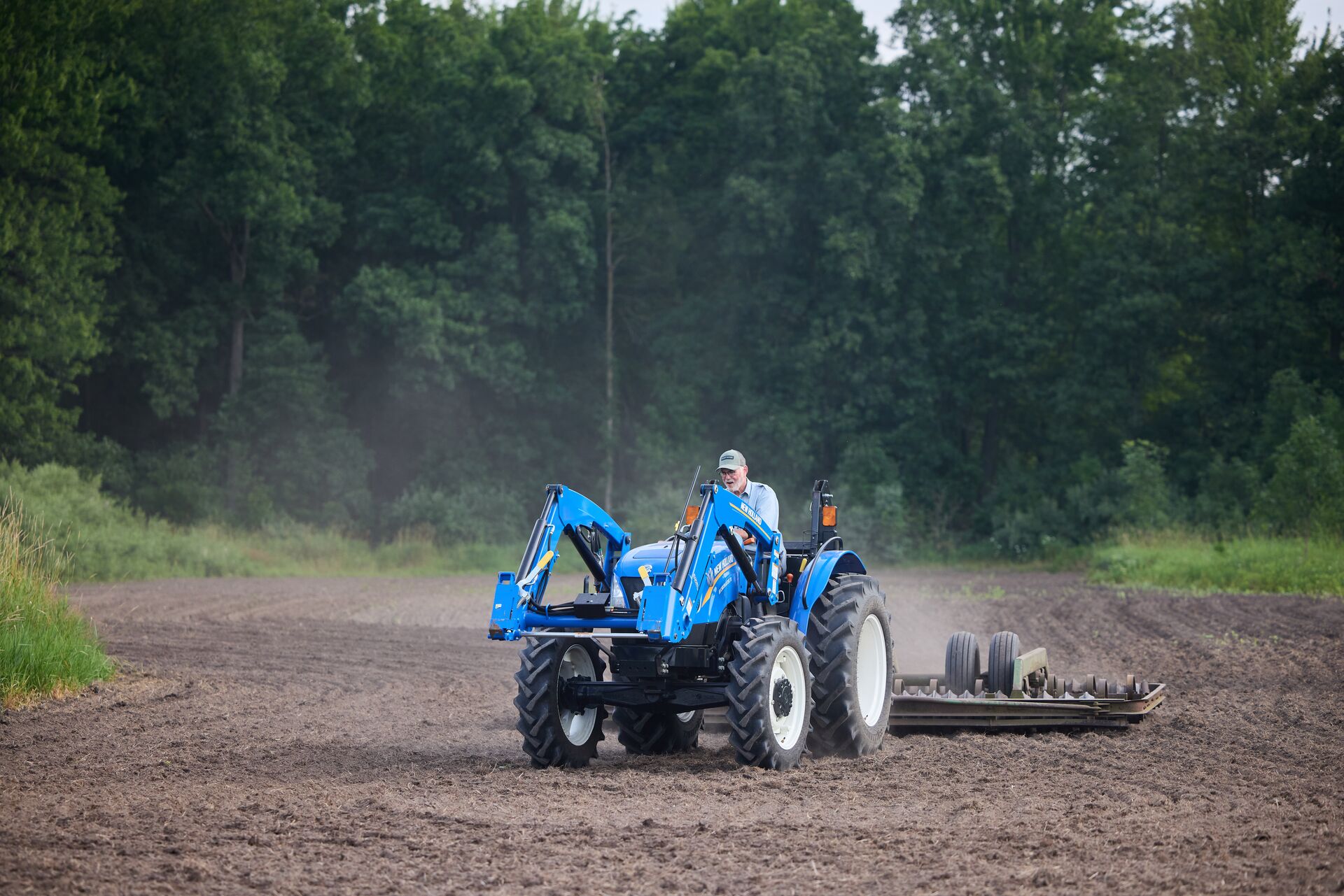 Man drives a blue tractor for habitat management. 