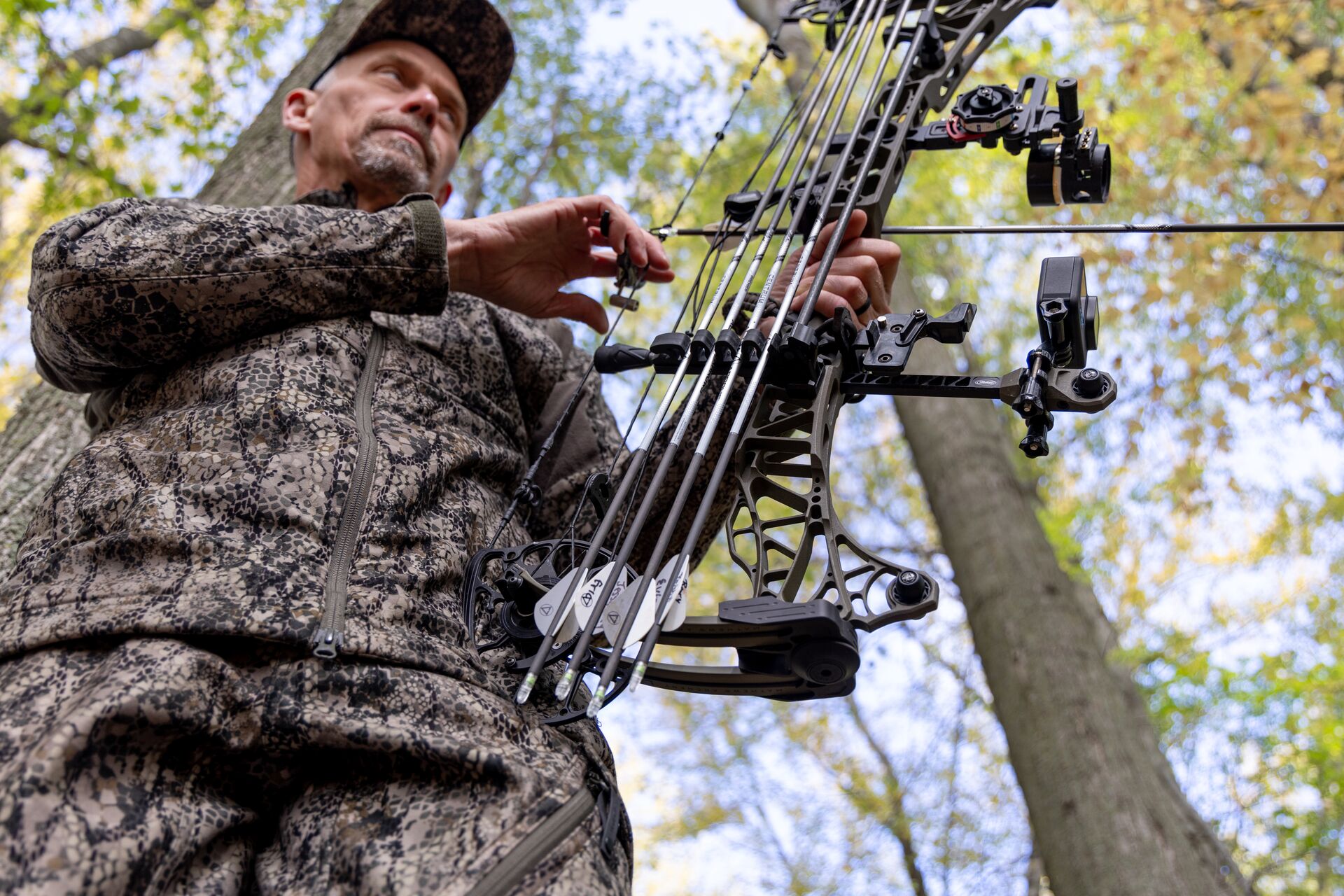 A hunter wears camo and holds a bow.