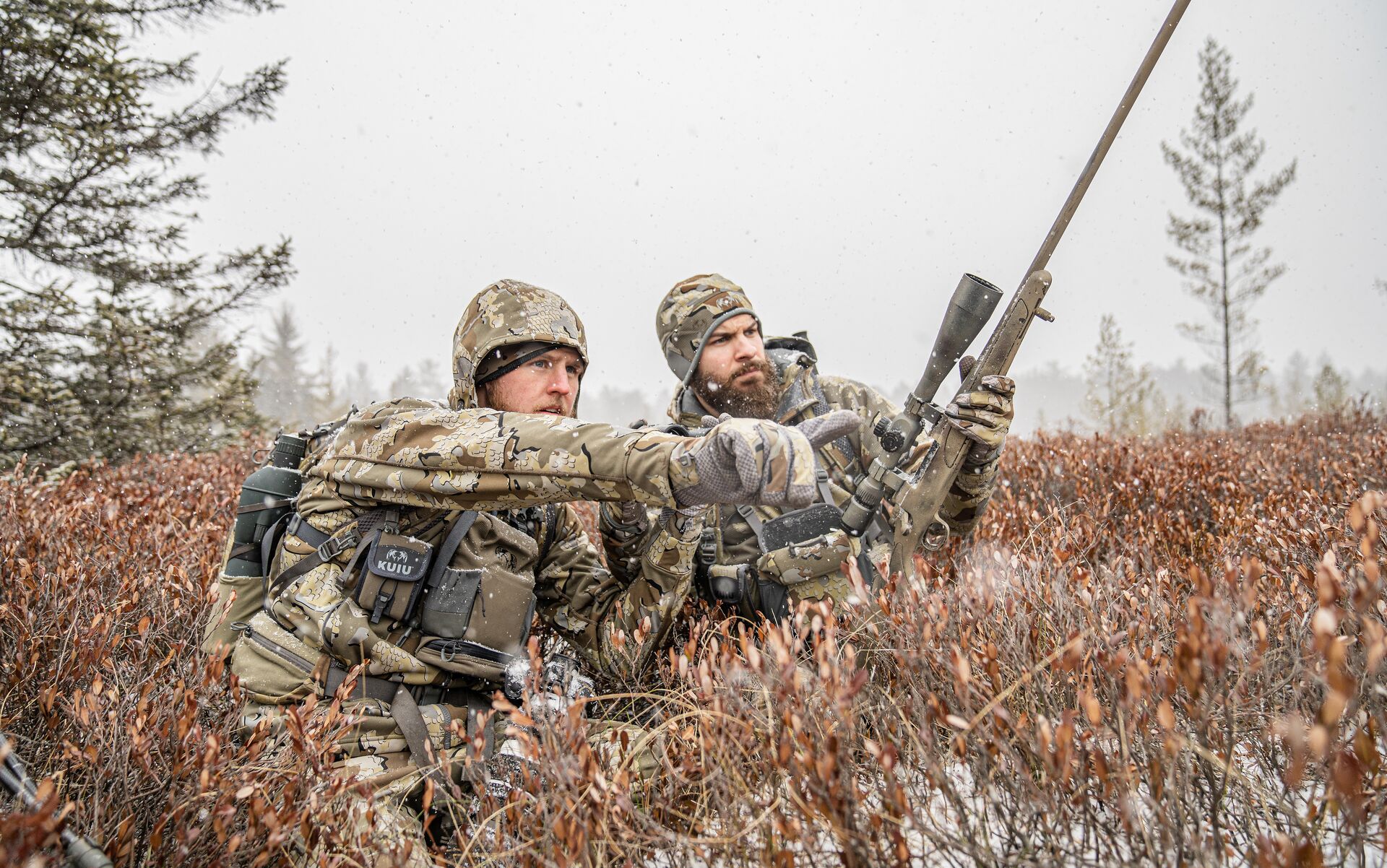 Two hunters in camo look and point, how far can a deer run after being shot concept.