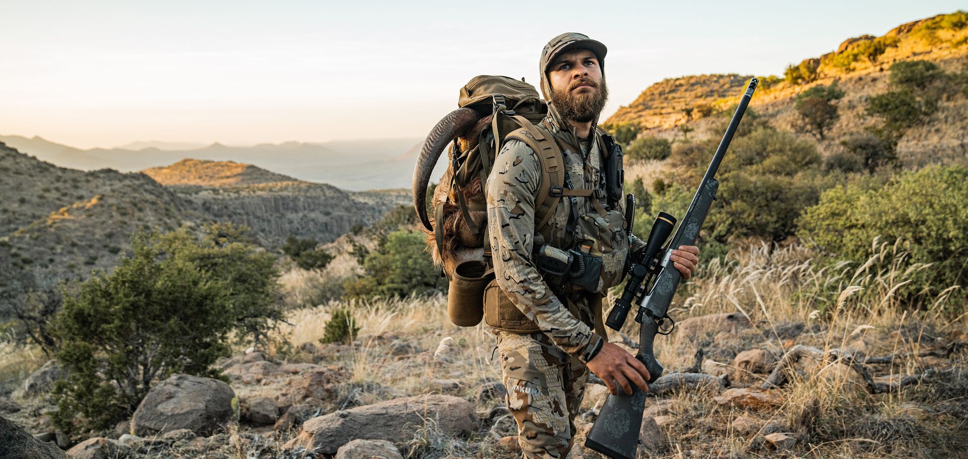 Hunter in camo with hunting pack and long range hunting rifle. 