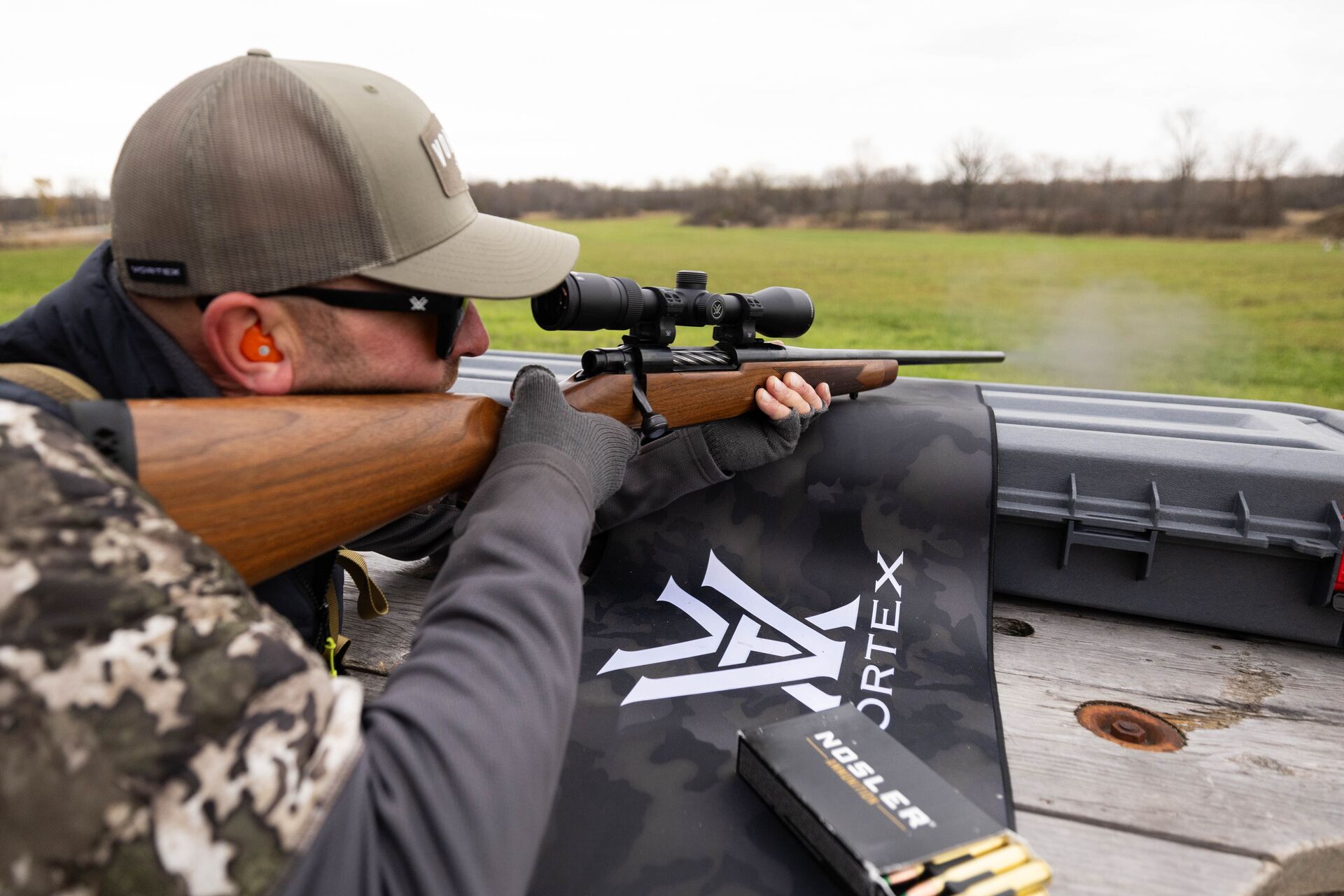 Hunter at practice range aims rifle. 