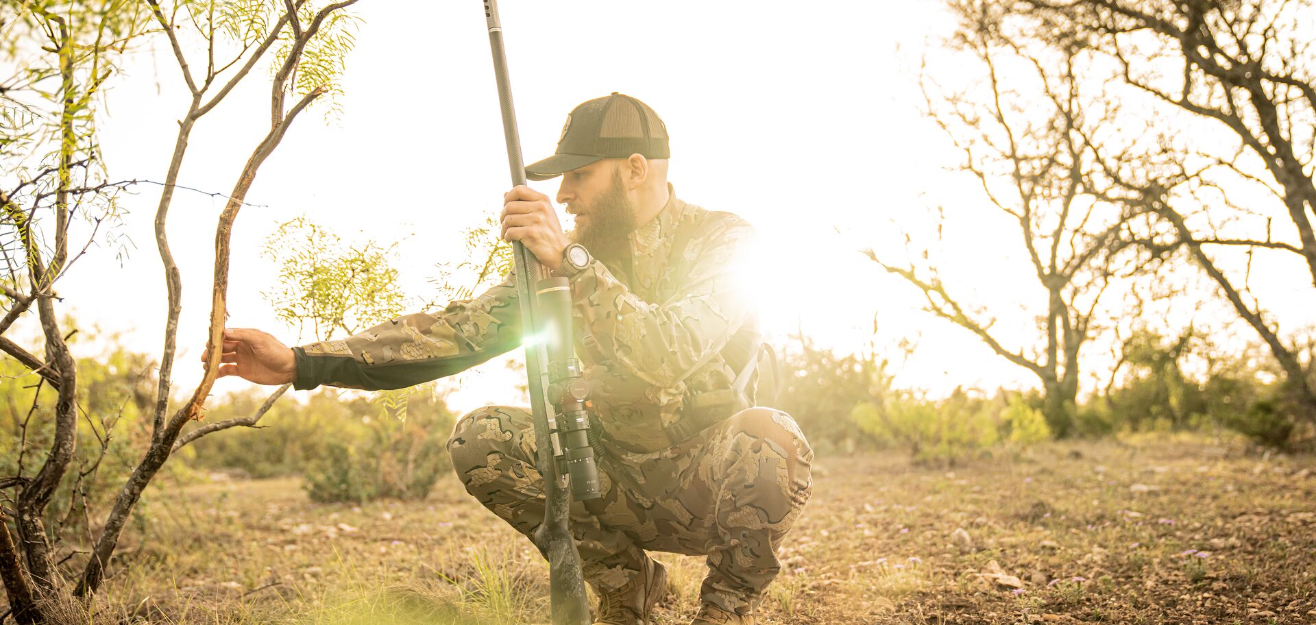 Hunter with rifle looks at tree scrape, scout for deer concept. 