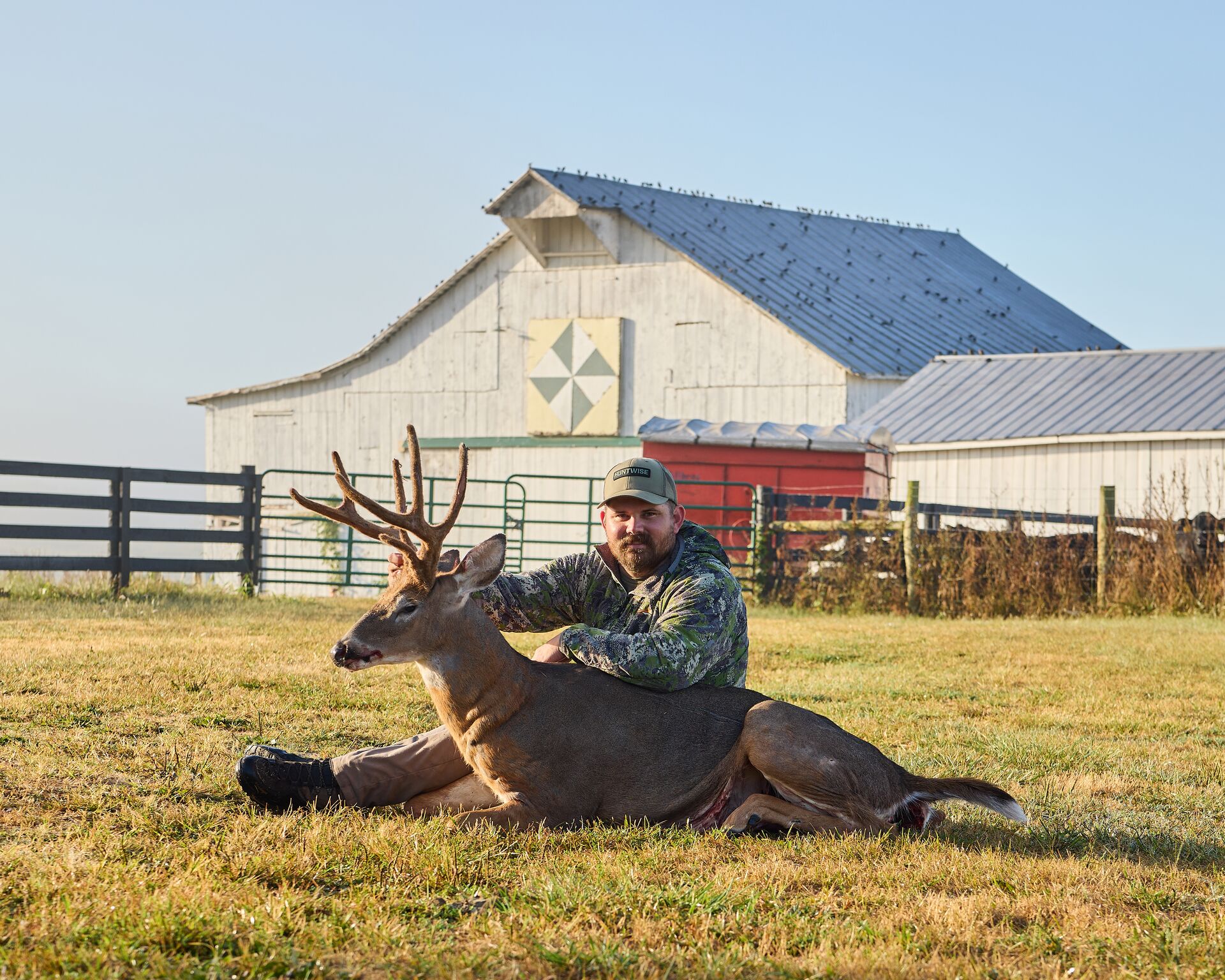 Hunter smiling with deer on the ground after hunt, scout for deer hunt concept. 