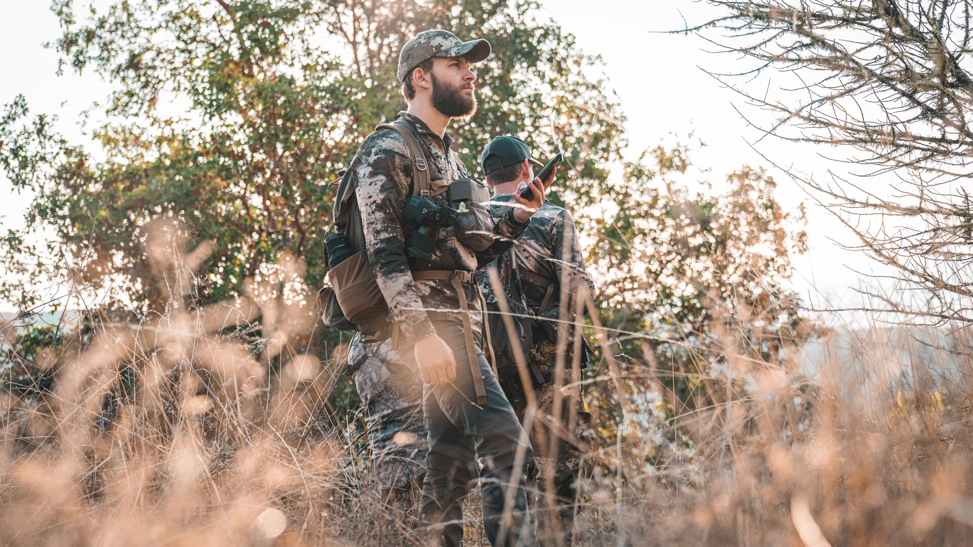 Two hunters with packs in the woods, hunting season preparation concept.