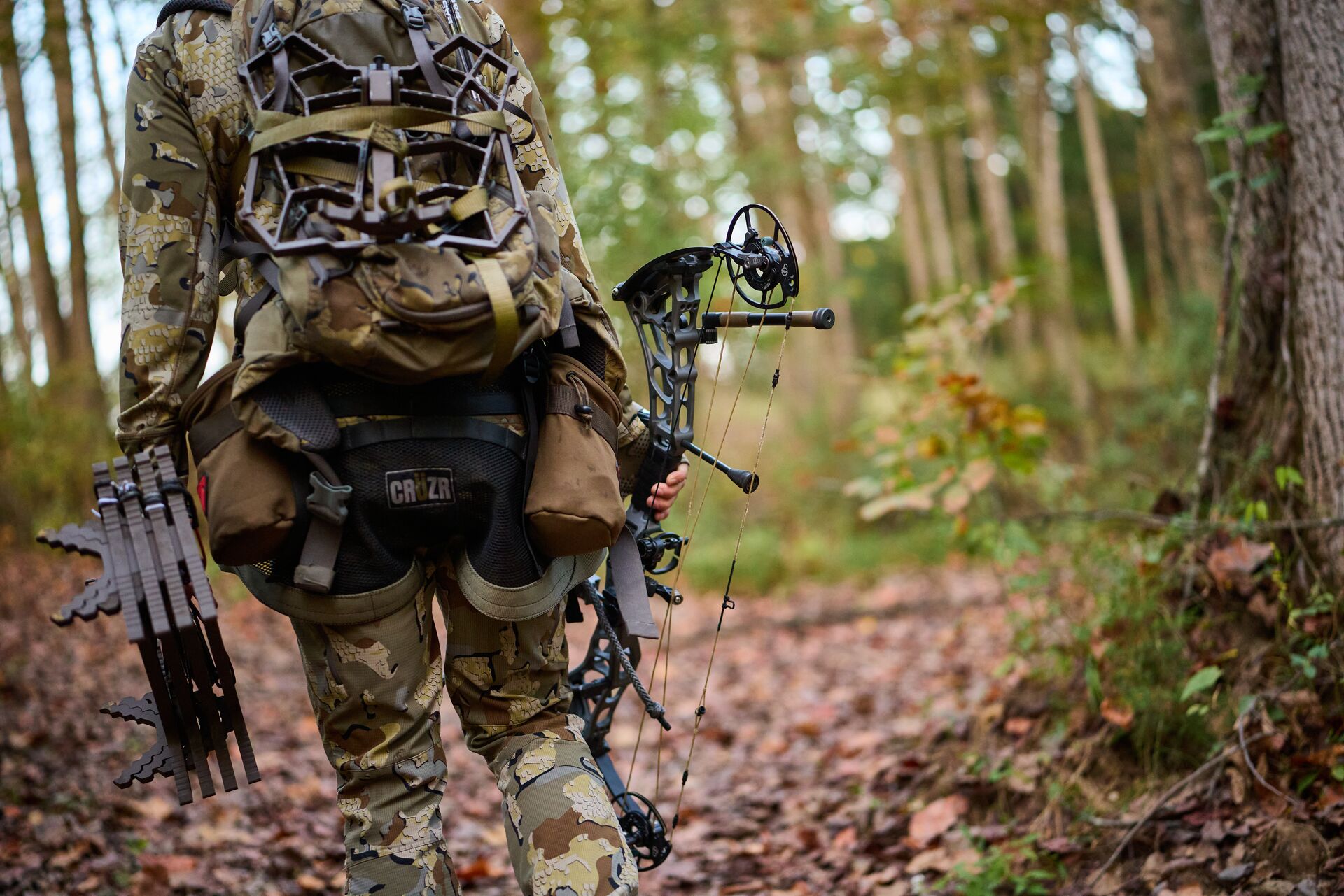 Hunter in camo with bow and gear in the woods, being a good hunting planner concept.