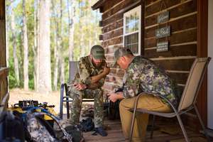 Two hunters sit together to plan a hunt, hunting planner concept.