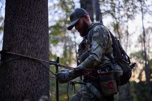 Hunter using safety system for tree saddle, hunting safety checklist concept.